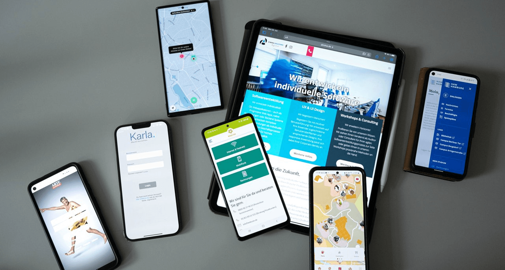Tisch mit mehreren Smartphones und Tablets, die von ATMINA entwickelte Apps zeigen